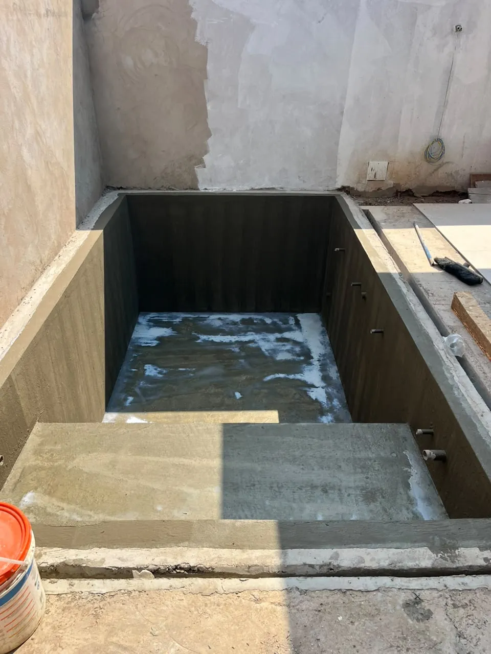 Piscina em obra com paredes revestidas e escada de concreto